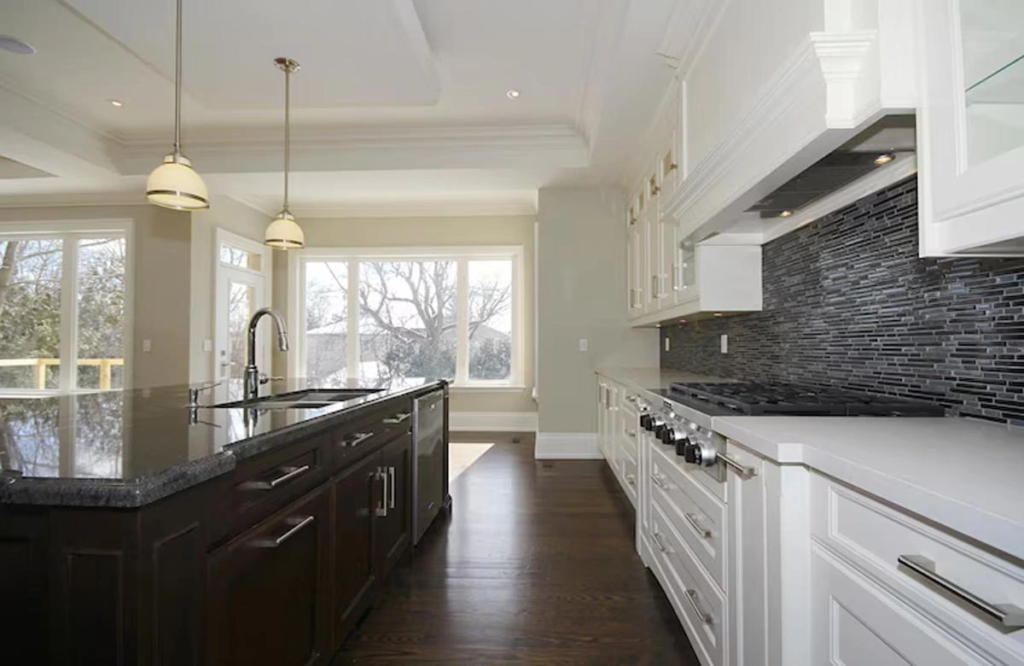 Discover refined kitchen renovation in Austin featuring sleek black countertops, white cabinetry, and a spacious island ideal for modern living.